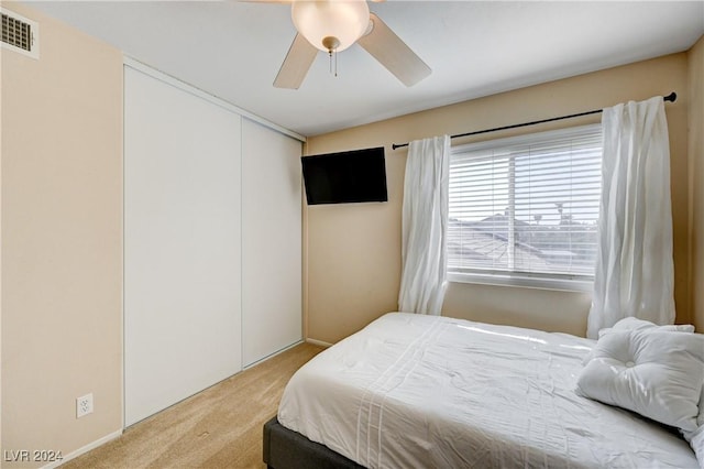 carpeted bedroom with ceiling fan and a closet