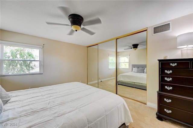 bedroom featuring ceiling fan, a closet, and light colored carpet