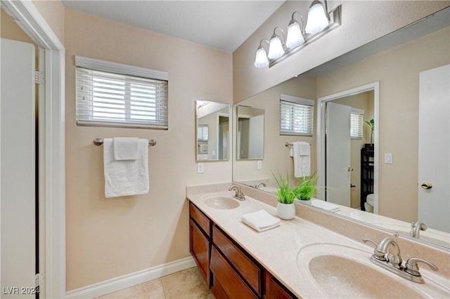 bathroom with tile patterned flooring, vanity, toilet, and a wealth of natural light