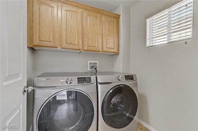 clothes washing area with washer and dryer and cabinets