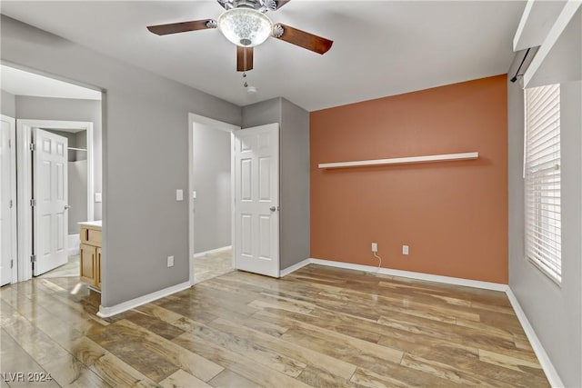 unfurnished bedroom featuring connected bathroom, ceiling fan, a closet, and light wood-type flooring