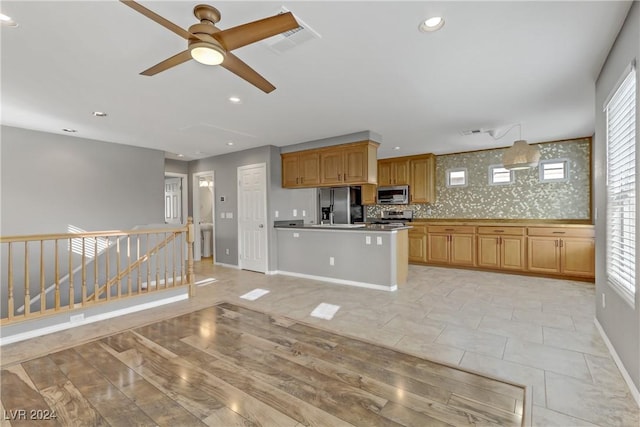 kitchen featuring a wealth of natural light, stainless steel appliances, decorative light fixtures, and light wood-type flooring