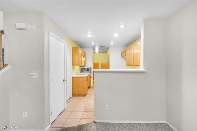 kitchen featuring kitchen peninsula, light brown cabinets, and light tile patterned flooring