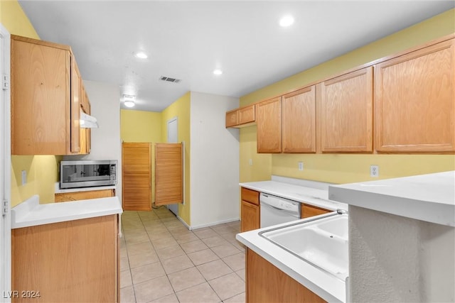 kitchen with light tile patterned floors, white dishwasher, and sink