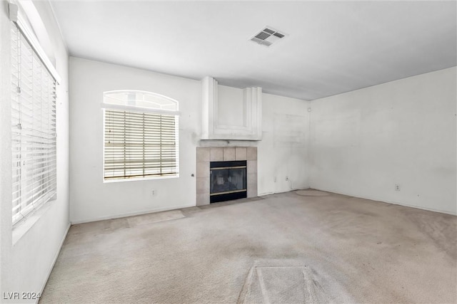 unfurnished living room featuring light carpet and a tiled fireplace