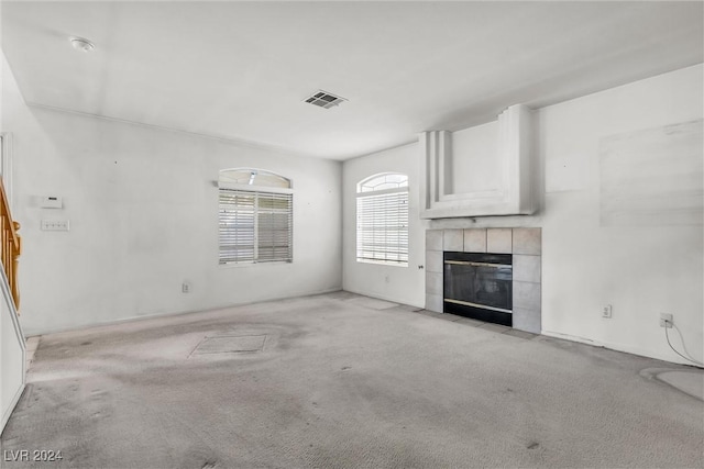 unfurnished living room with a tile fireplace and light carpet