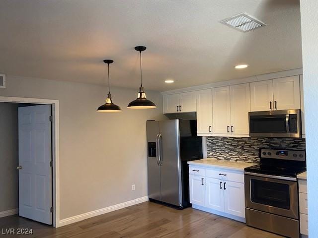 kitchen featuring dark wood-type flooring, hanging light fixtures, decorative backsplash, white cabinetry, and stainless steel appliances