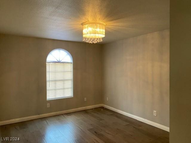 spare room featuring dark hardwood / wood-style flooring and a chandelier