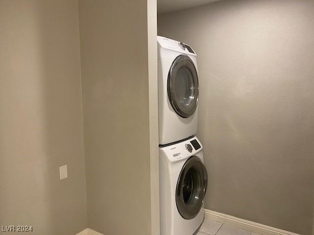 washroom featuring stacked washer and dryer and light tile patterned floors