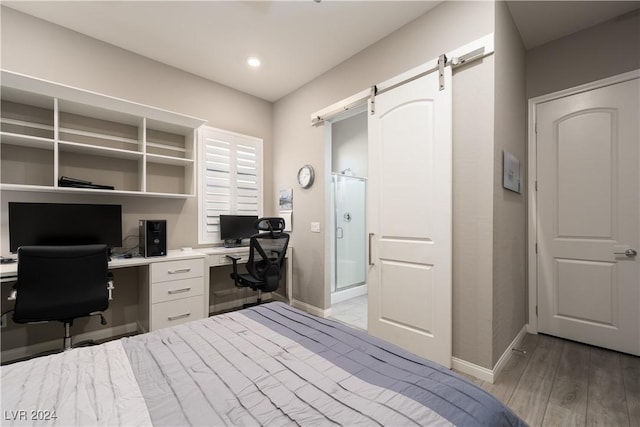 bedroom featuring a barn door and light hardwood / wood-style flooring