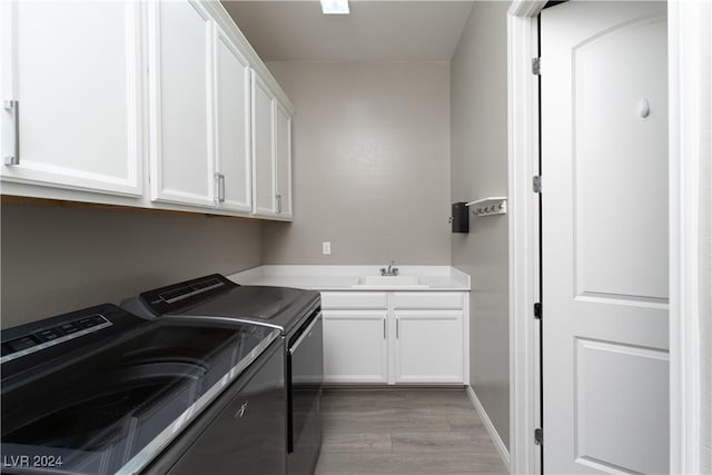 laundry area featuring cabinets, light hardwood / wood-style flooring, washer and clothes dryer, and sink