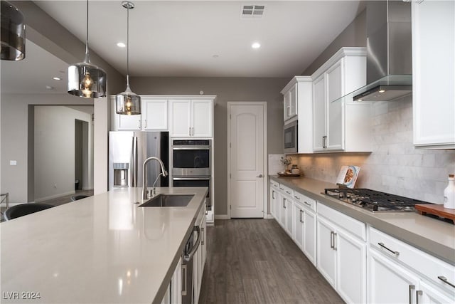 kitchen with sink, white cabinetry, decorative light fixtures, stainless steel appliances, and wall chimney exhaust hood