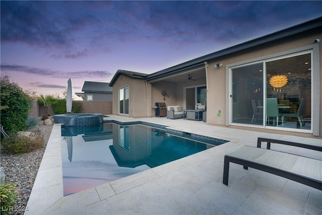 pool at dusk featuring a patio area, grilling area, ceiling fan, and an in ground hot tub