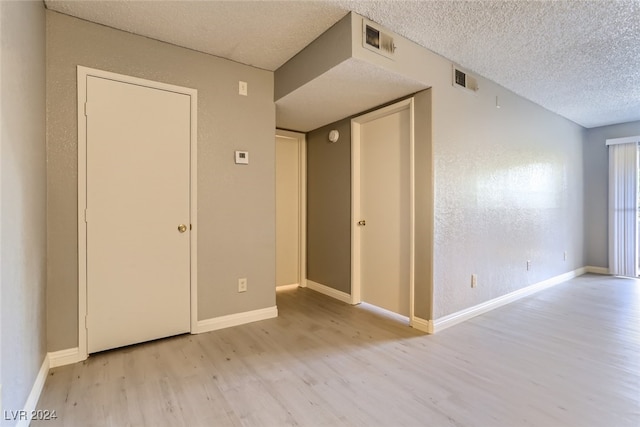 empty room with a textured ceiling and light wood-type flooring