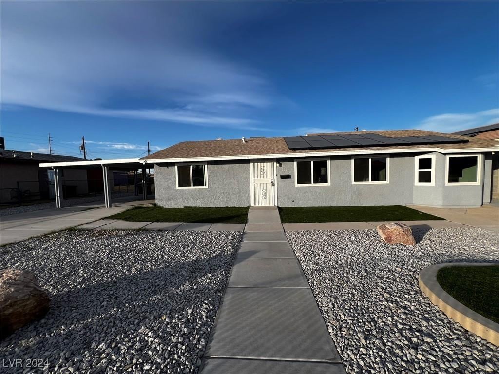 view of front of home with solar panels and a carport