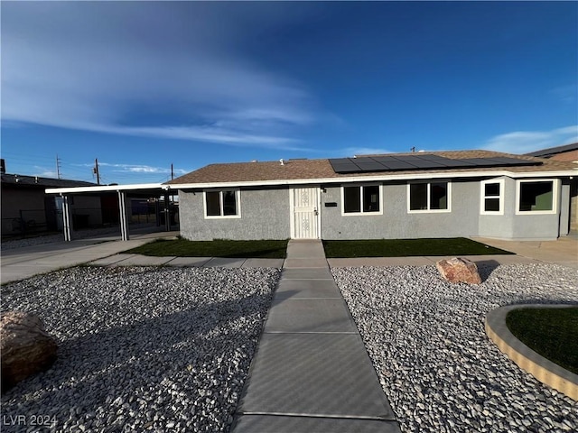 view of front of home with solar panels and a carport