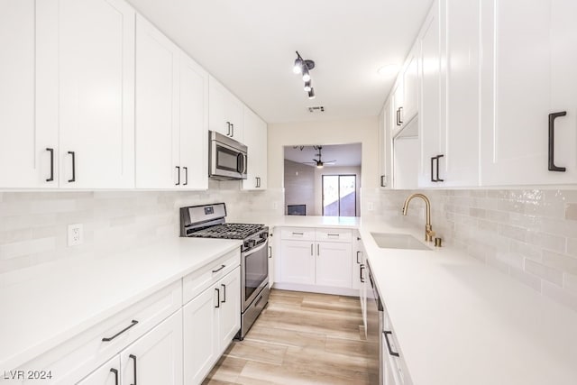 kitchen with backsplash, stainless steel appliances, sink, light hardwood / wood-style floors, and white cabinetry