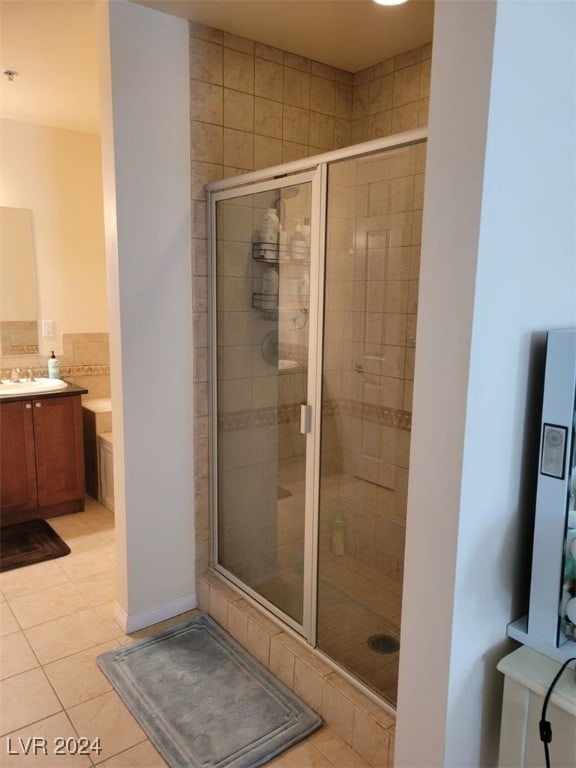 bathroom with tile patterned floors, a shower with door, and vanity