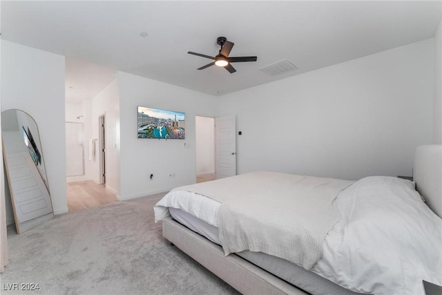 bedroom with light carpet, ensuite bath, and ceiling fan