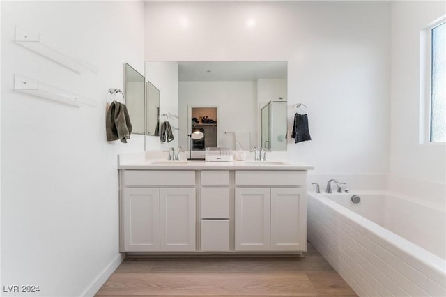 bathroom featuring vanity, hardwood / wood-style flooring, and a relaxing tiled tub
