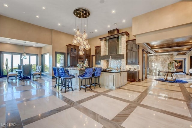 kitchen with a large island, a towering ceiling, hanging light fixtures, and a breakfast bar area