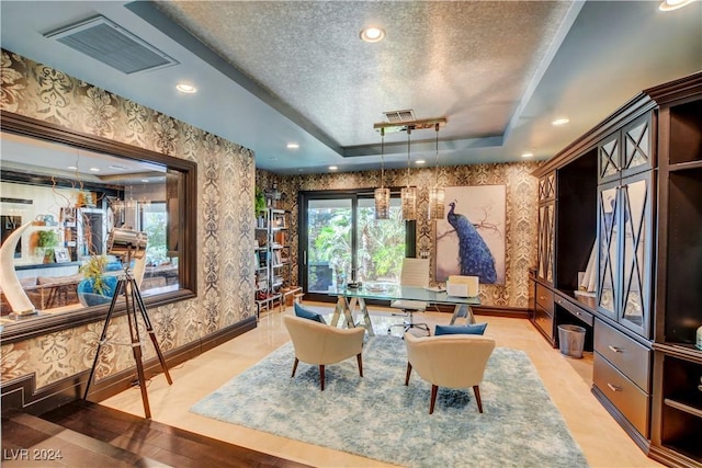 sitting room featuring a raised ceiling and a textured ceiling