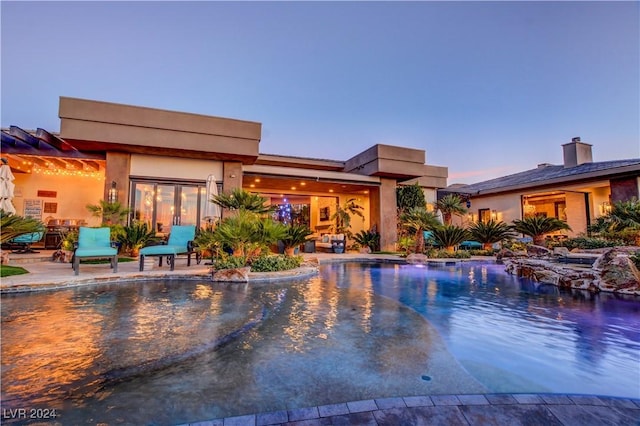 pool at dusk featuring a patio