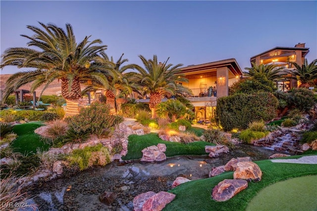 yard at dusk featuring a balcony