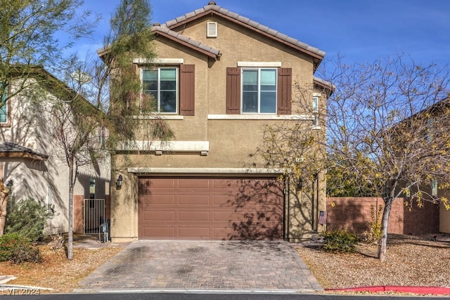 view of front of home with a garage, a tiled roof, decorative driveway, and stucco siding