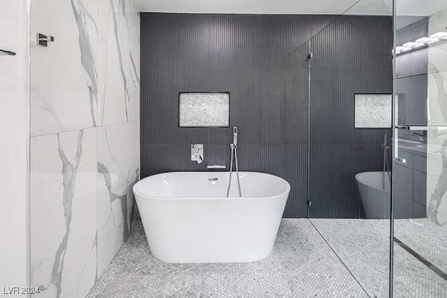 bathroom featuring a bath and tile walls