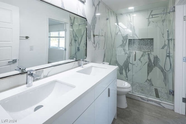 bathroom with a shower with door, vanity, wood-type flooring, and toilet