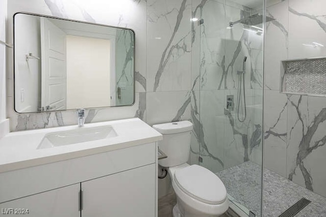 bathroom with tiled shower, vanity, toilet, and tile walls