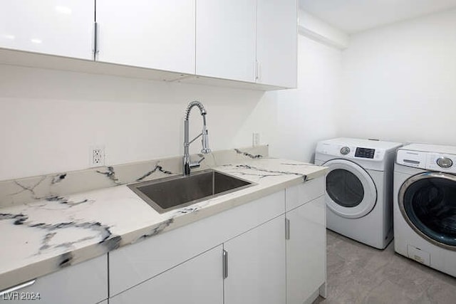 washroom with cabinets, independent washer and dryer, and sink