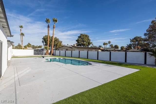 view of pool featuring a lawn and a storage unit