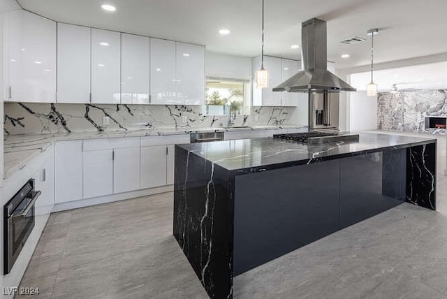 kitchen with pendant lighting, appliances with stainless steel finishes, white cabinets, and range hood