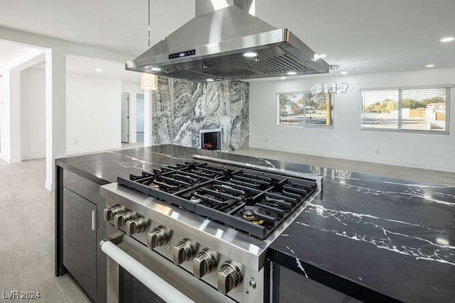 kitchen featuring high end stainless steel range, a high end fireplace, hanging light fixtures, and ventilation hood