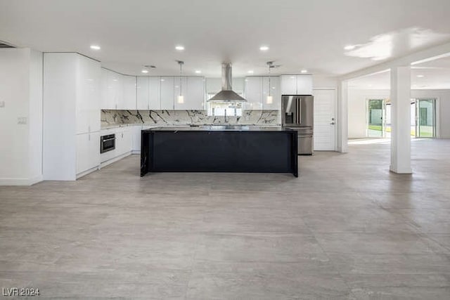 kitchen featuring white cabinets, wall chimney range hood, stainless steel refrigerator with ice dispenser, hanging light fixtures, and decorative backsplash