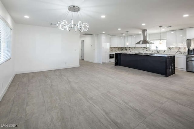 kitchen with backsplash, wall chimney exhaust hood, decorative light fixtures, white cabinets, and a kitchen island