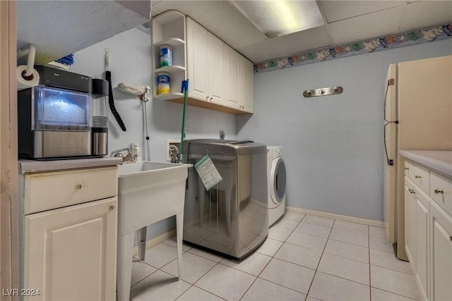 laundry area with light tile patterned floors, washing machine and dryer, cabinet space, and baseboards