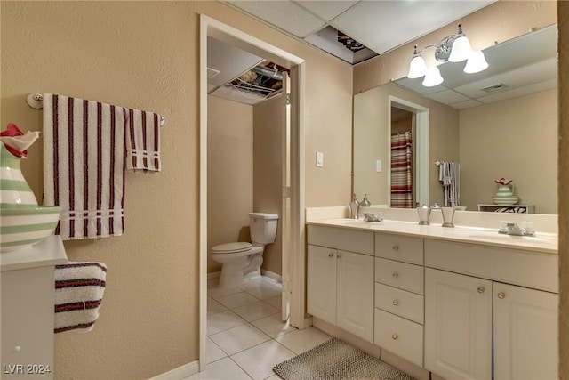 full bath with a paneled ceiling, double vanity, a sink, and tile patterned floors