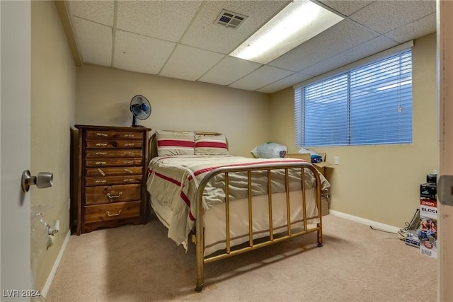 carpeted bedroom with a paneled ceiling, baseboards, and visible vents