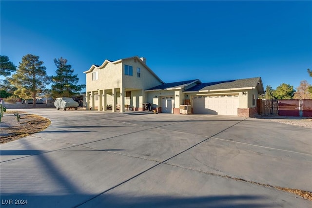 view of front of home with a garage, driveway, fence, and stucco siding