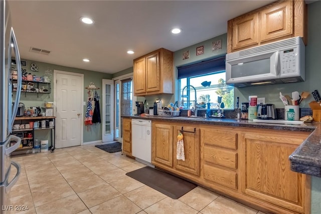 kitchen featuring recessed lighting, white appliances, light tile patterned flooring, and a sink