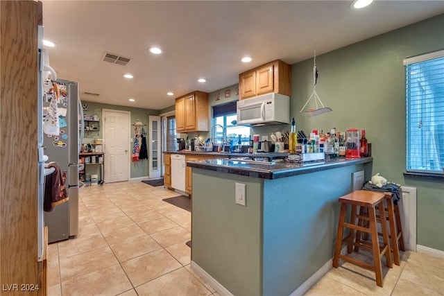 kitchen with white appliances, light tile patterned floors, visible vents, a peninsula, and recessed lighting