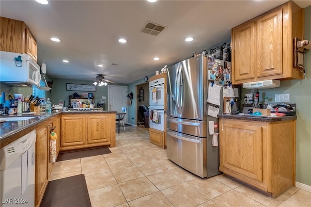 kitchen with dark countertops, visible vents, ceiling fan, white appliances, and a peninsula