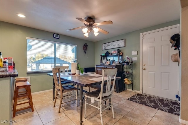 dining space with a ceiling fan, baseboards, and light tile patterned floors