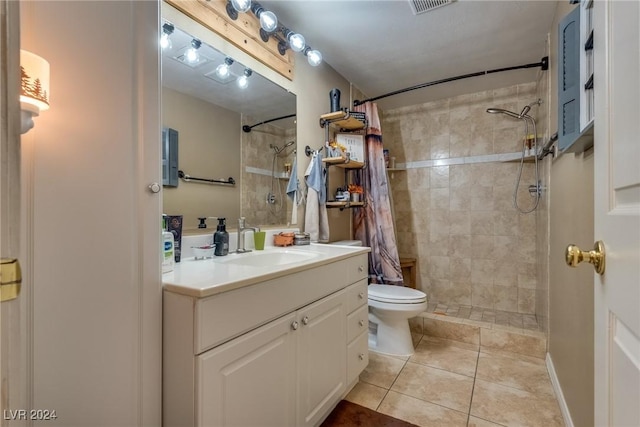 bathroom with visible vents, toilet, tile patterned flooring, a tile shower, and vanity