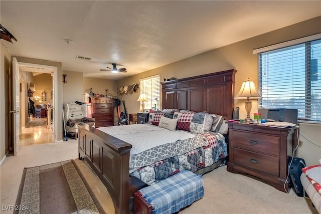 bedroom with light carpet, ceiling fan, multiple windows, and visible vents