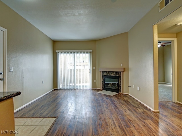 unfurnished living room with ceiling fan, wood-type flooring, and a premium fireplace