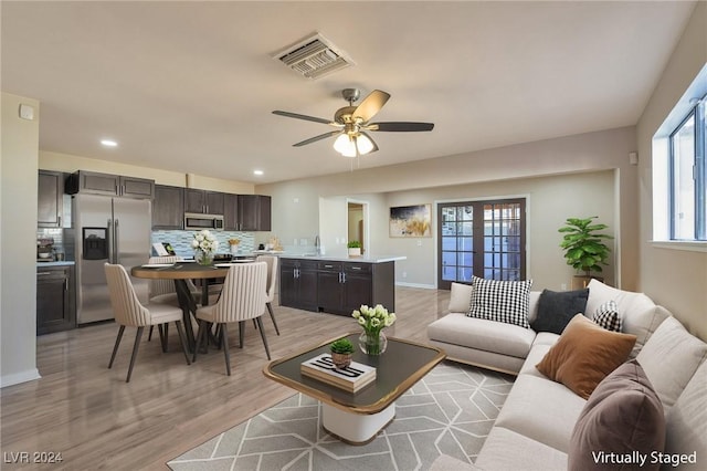 living room with ceiling fan, light wood-type flooring, and sink